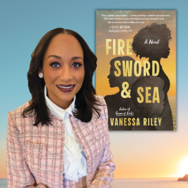 A person wearing a light pink tweed jacket and white ruffled blouse stands in front of a large book cover. The book displayed is titled Fire, Sword & Sea: A Novel by Vanessa Riley, featuring silhouettes of three figures against a sunset-colored background.