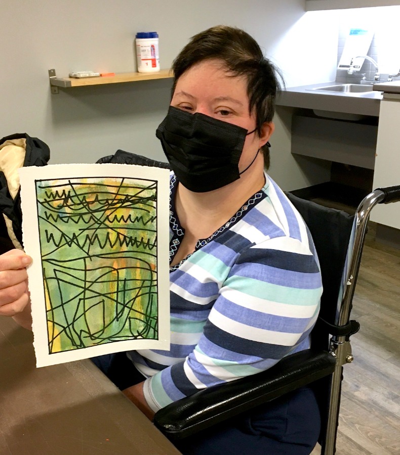 girl in wheelchair holding up her artwork