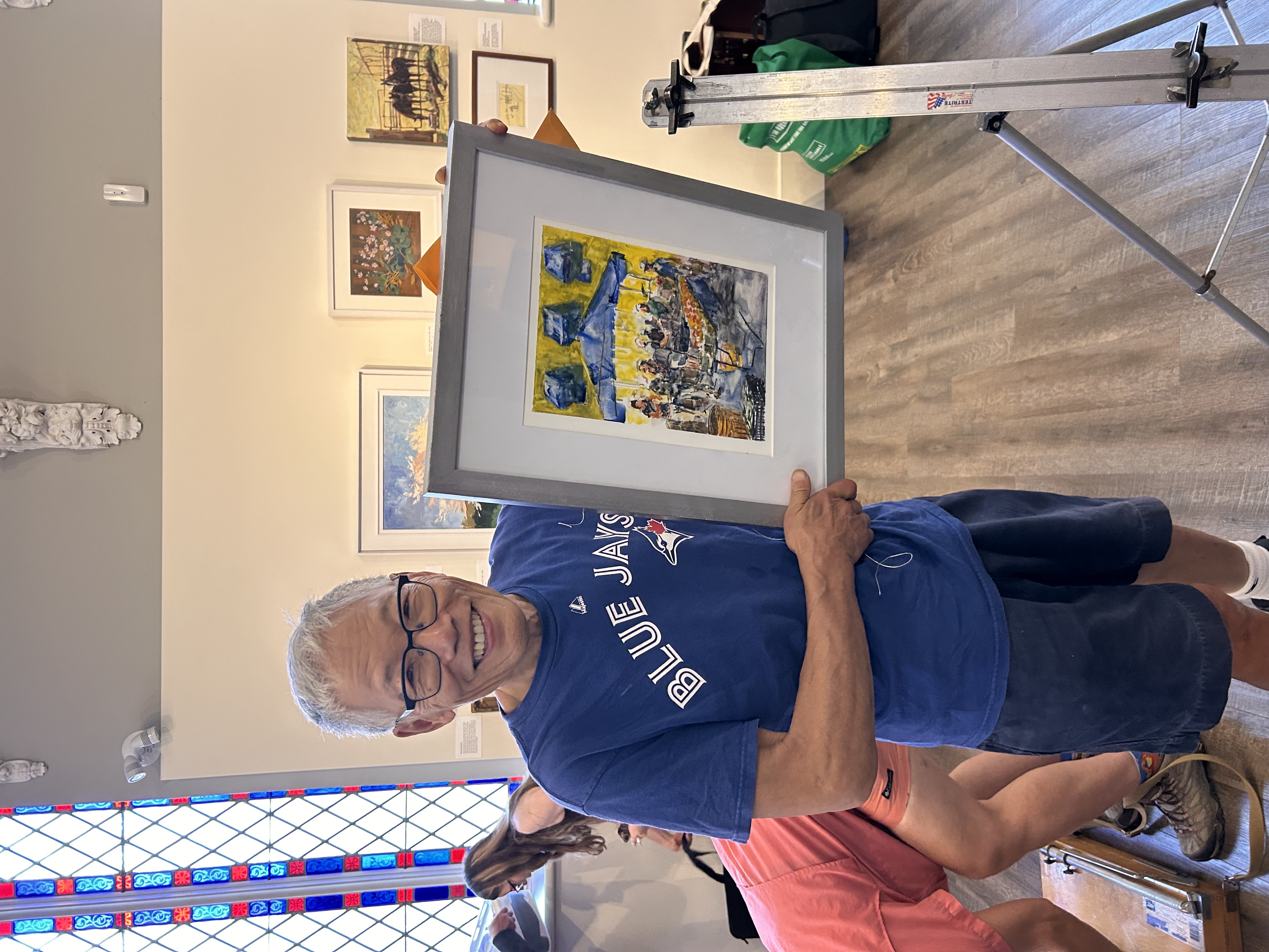 A man smiling while holding a painting