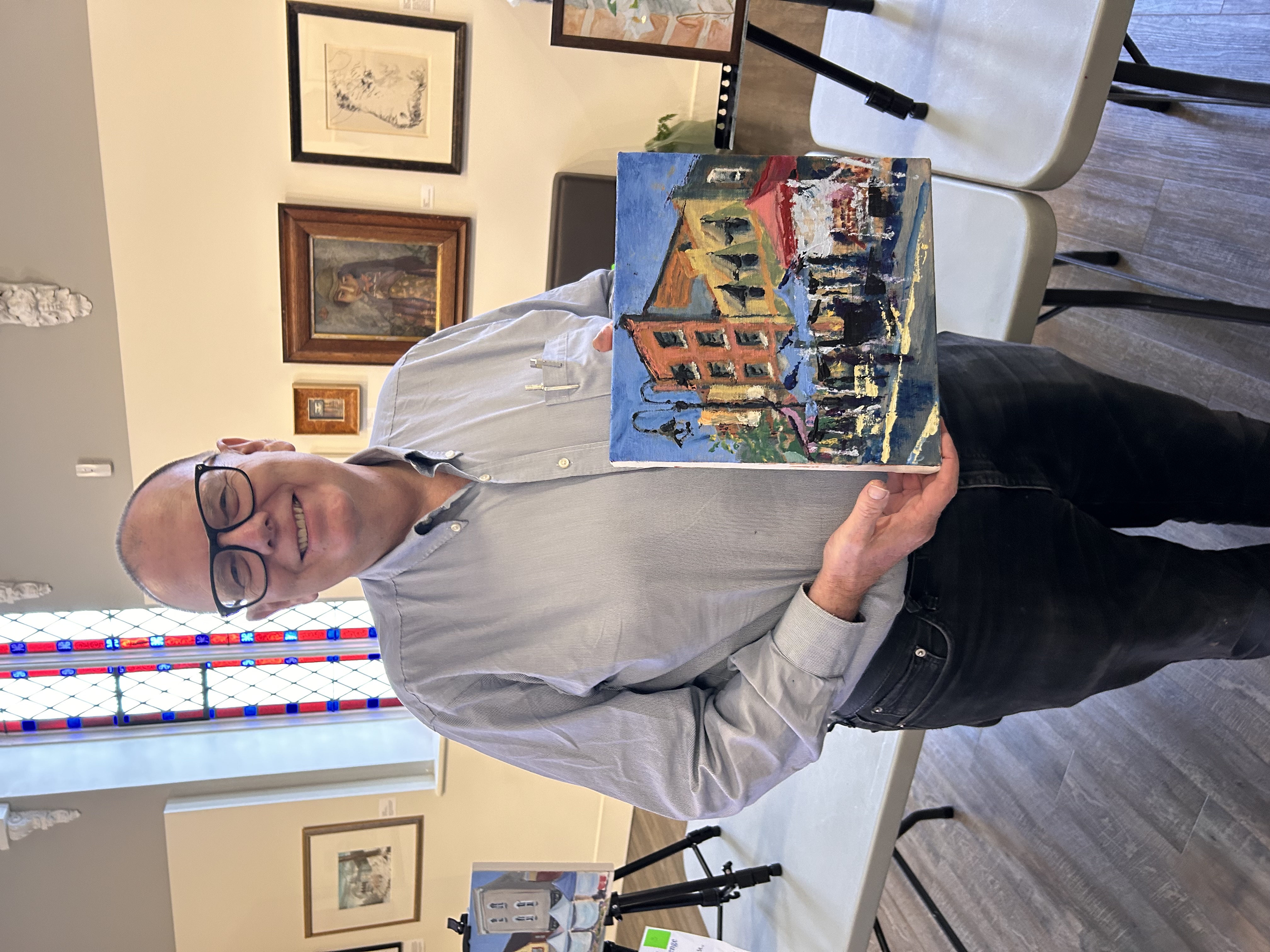 A man smiling while holding a painting