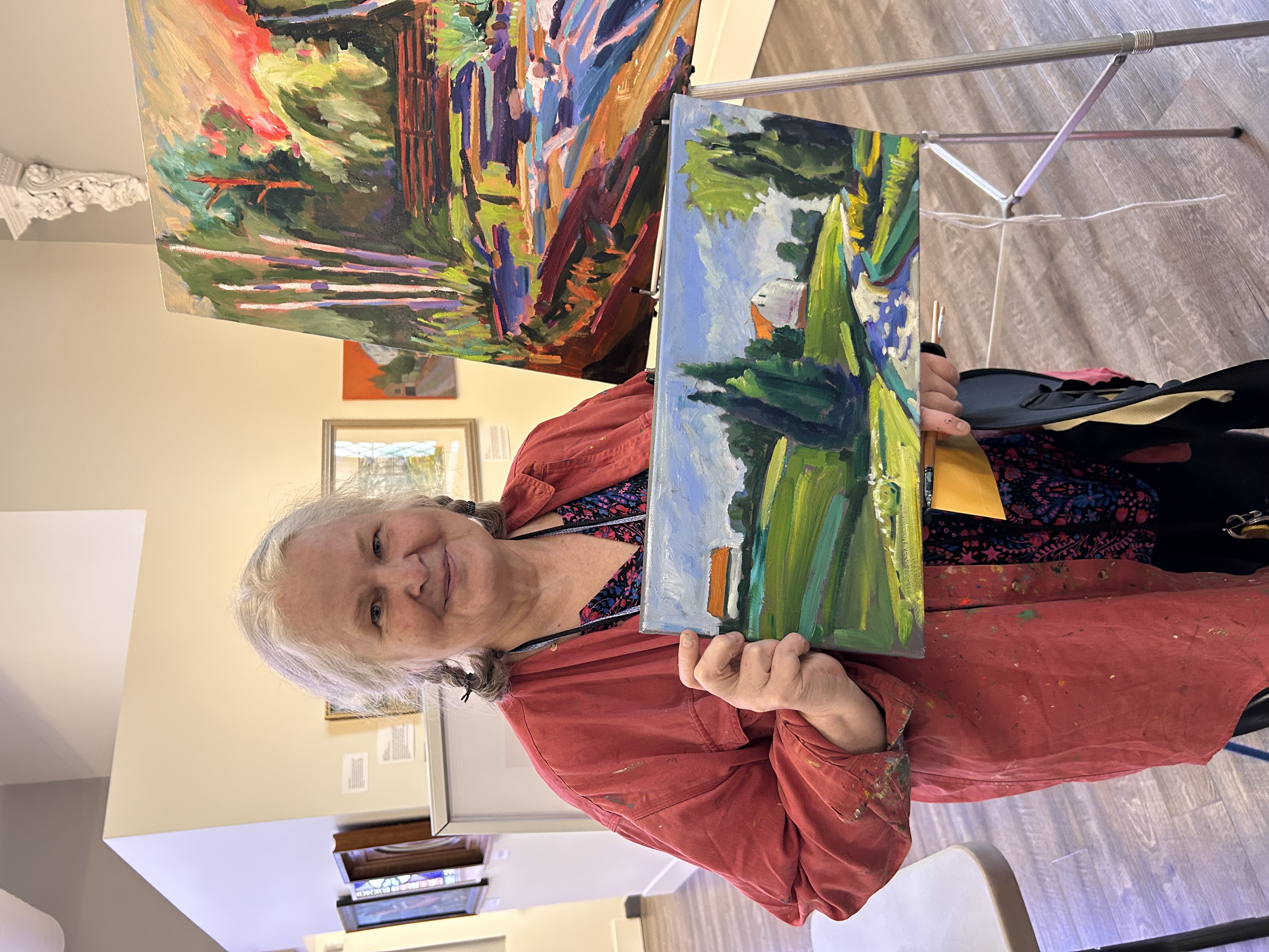 A woman smiling while holding a painting