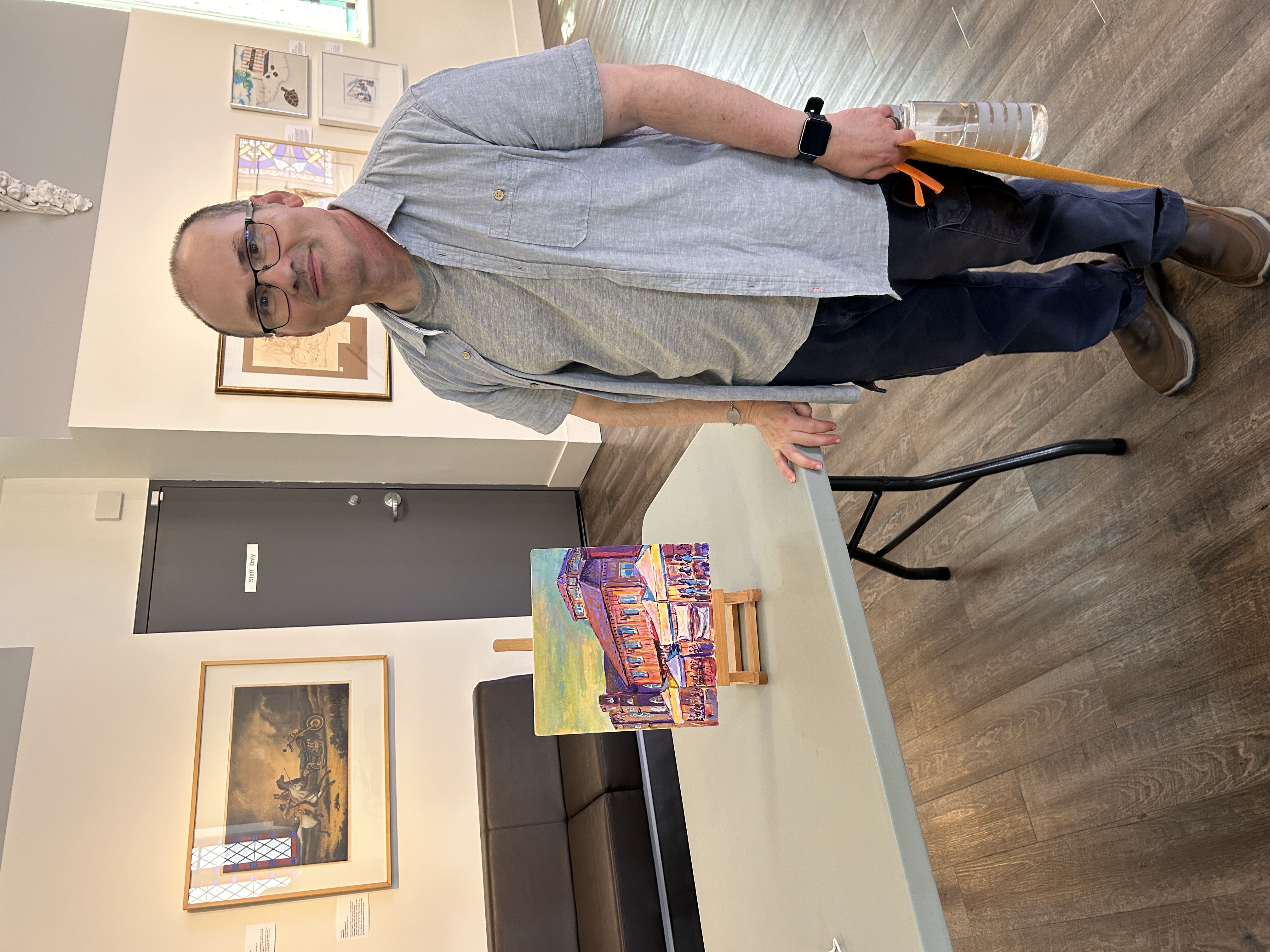 A man smiling while holding a painting