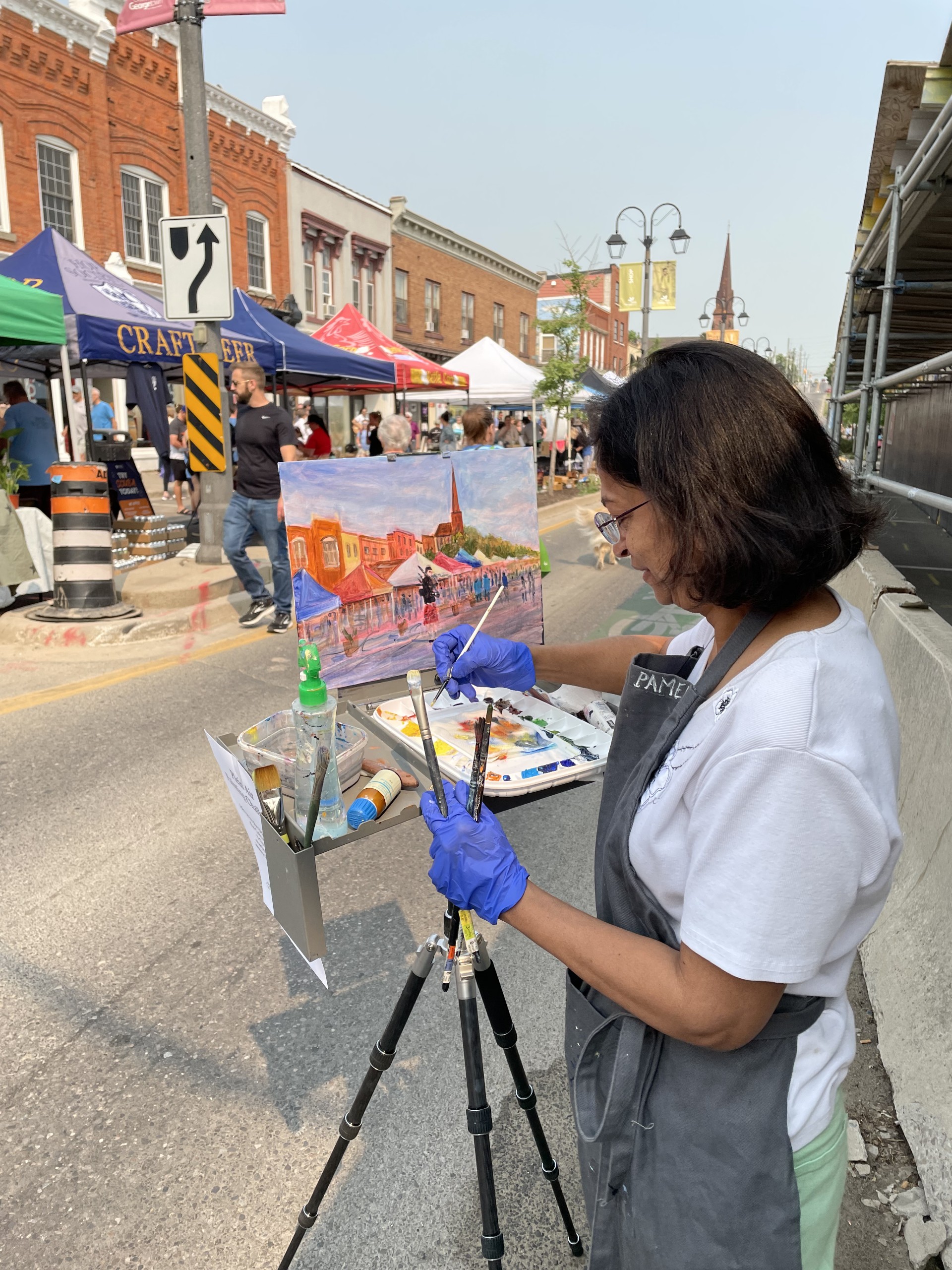 A person paints at an easel and canvas outside in plein air