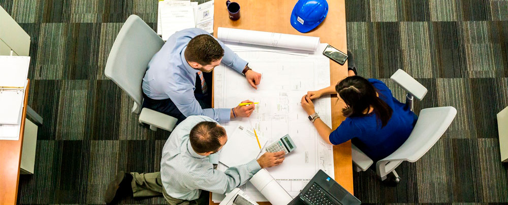 group of employees gathered around a table reviewing plans