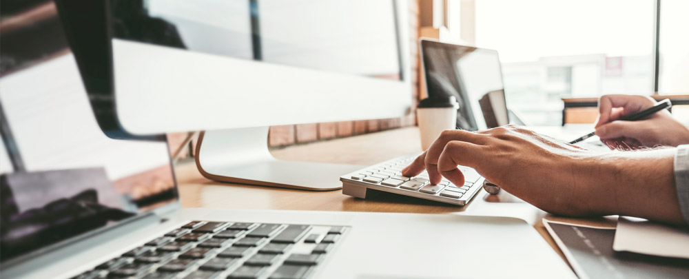 closeup of person using two computers to browse information