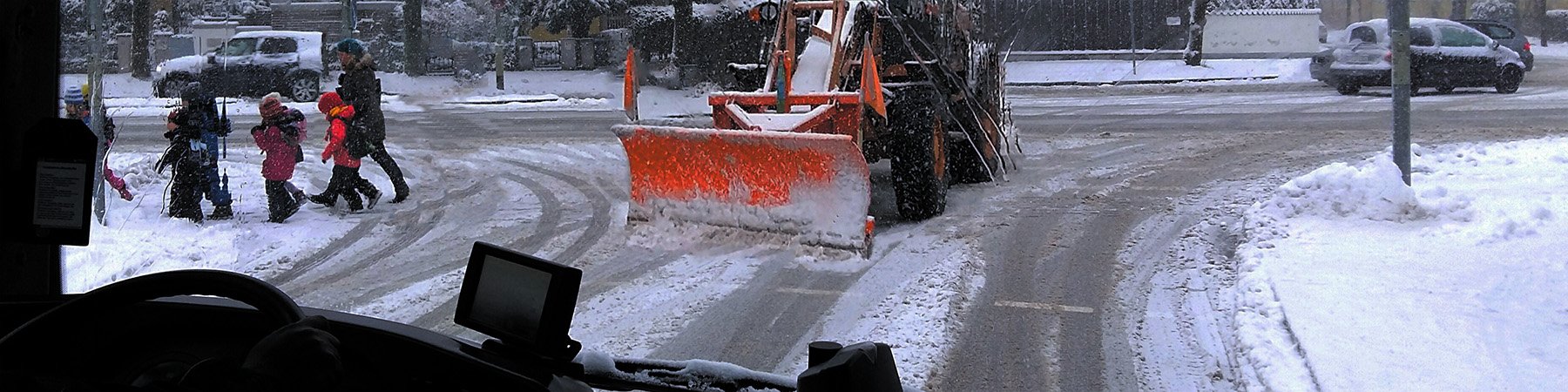 View from inside a bus and a plow and children on the sidewalk