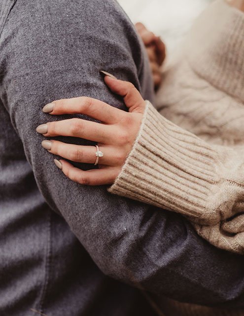 a man and a woman hugging showing off engagement ring