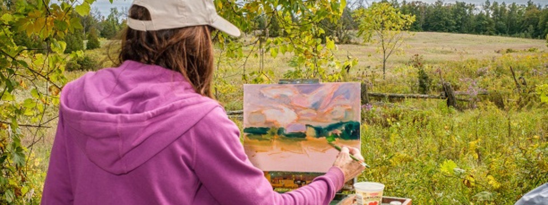 An image of a woman painting outdoors