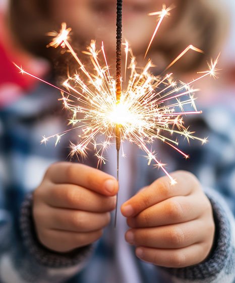 A child holding a single lit sparkler in front of them