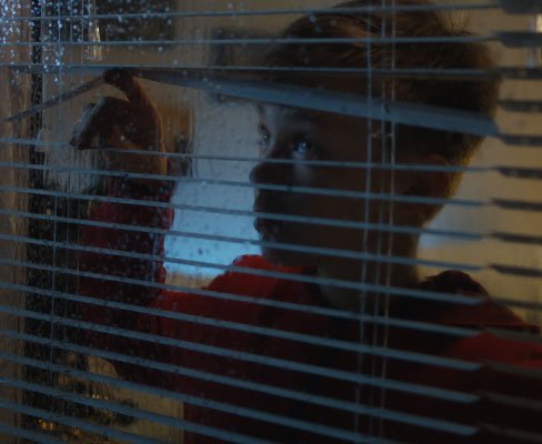 Child watching the rain through the window