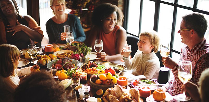 People of various ages and races sitting at a table for Thanksgiving