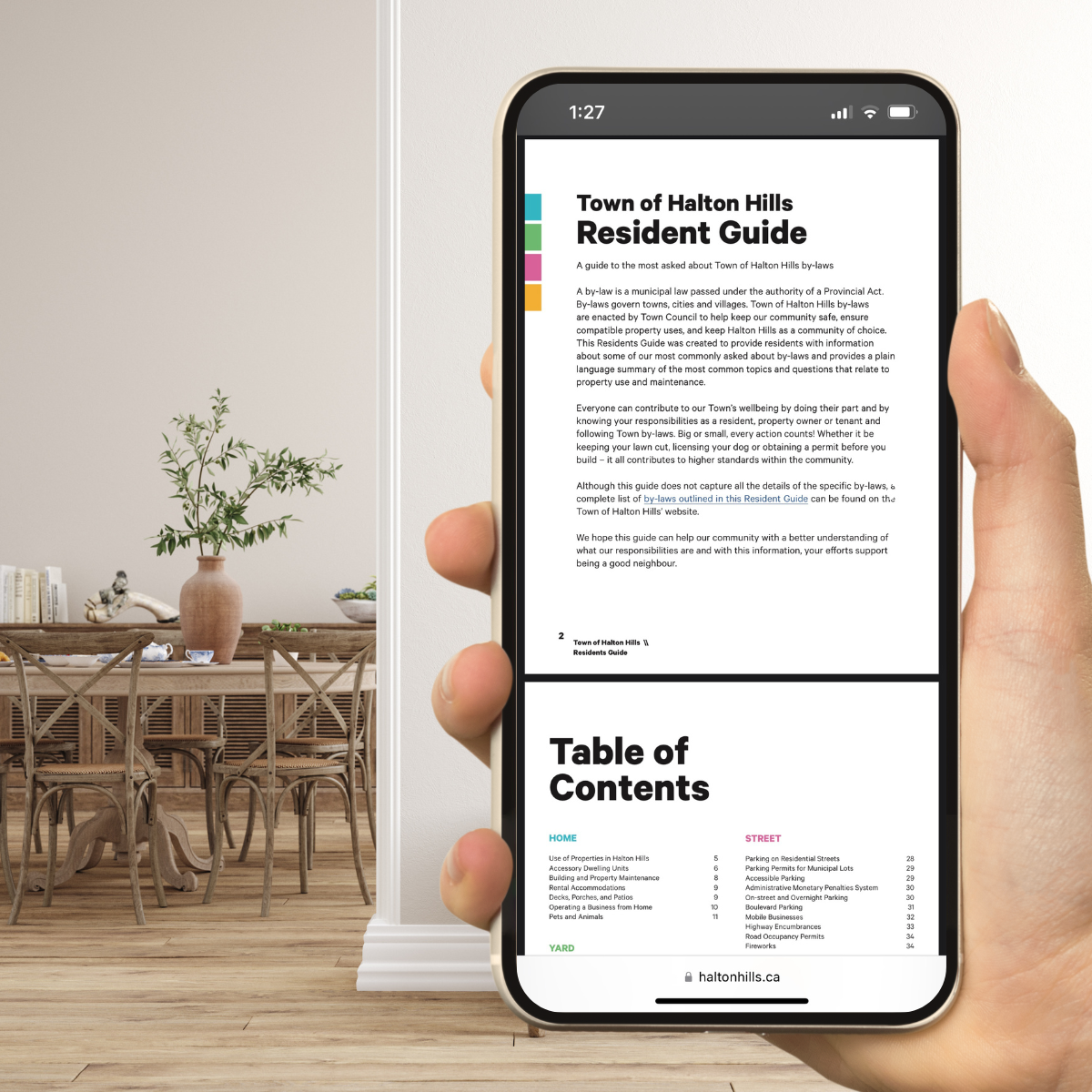 Hand holding up phone with Residents Guide loaded and dinning area in the background