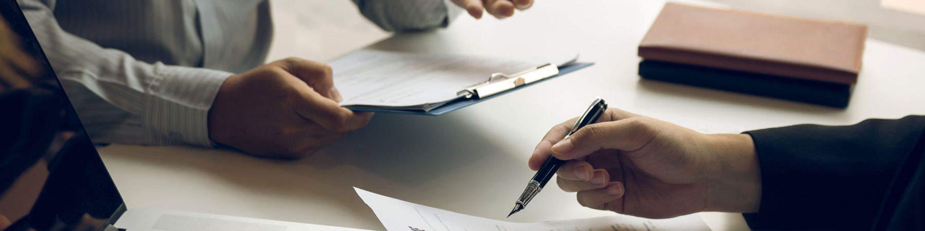 Two people's hands over desk with documents